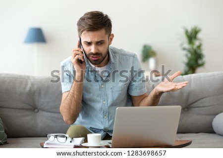 Angry man talking on phone disputing over computer laptop problem, stressed unsatisfied impatient customer arguing by mobile solving online difficulty with technical support complain on bad service