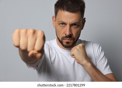 Angry Man Throwing Punch On Grey Background