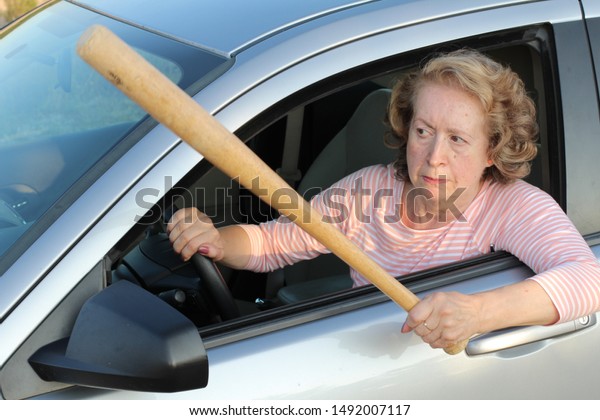 Angry mature\
female driver holding baseball bat\
