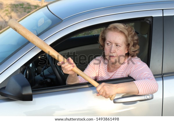 Angry mature\
female driver holding baseball\
bat