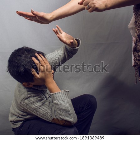 angry mother beat up sad boy on gray background
