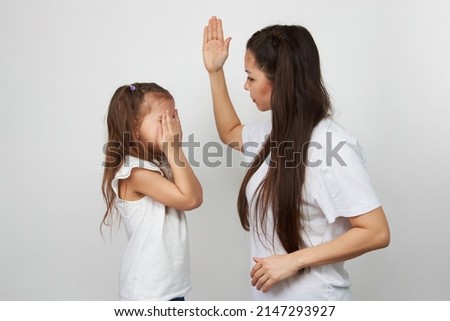 Angry mother beat up sad daughter on white background. Mom hit her kid. Young mother scolds her child girl