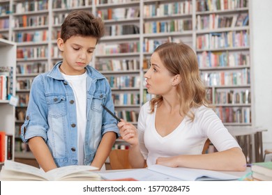 Angry Mother Scolding Her Son At The Library. Annoyed Mom Blaming Her Child For Bad Behaviour Or Marks At School