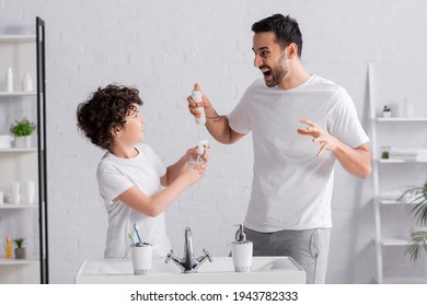 Angry Muslim Man Holding Deodorant Near Son With Sprayer