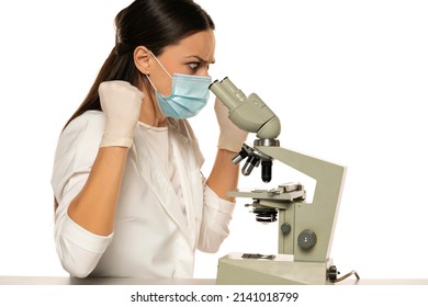 Angry Nervous Female Scientist With Protective Face Mask Looking Through A Microscope, White Background