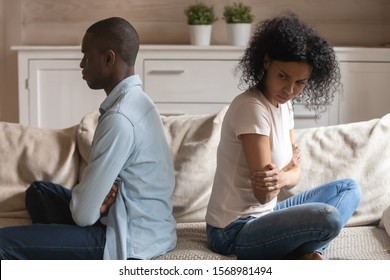 Angry Offended African American Husband And Wife Sit On Sofa Separately Back To Back Avoid Talking After Fight, Mad Biracial Couple Ignore Each Other After Family Quarrel, Divorce, Breakup Concept