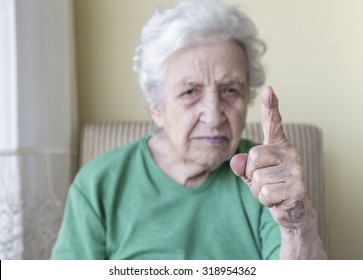an angry old woman with her finger up for admonition /warning