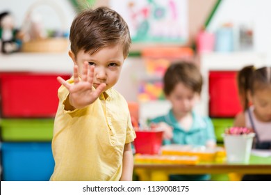 Angry preschool student doing stop sign in classroom