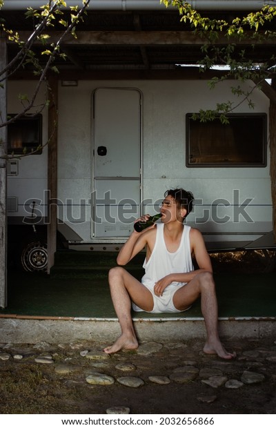 An\
angry and rude man with a bottle of booze stands at the camper.\
Travel and camping. The marginal stratum of\
society.