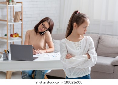 Angry Sad Teenage Girl Taking Offence At Her Busy Mother Working Online From Home, Empty Space. Child Feeling Neglected And Lonely With Her Mom Having Remote Job During Covid-19 Lockdown