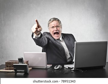 Angry senior businessman sitting at his desk and screaming - Powered by Shutterstock