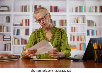 Angry Stressed Businesswoman Opening Envelope Reading Bad News In Mail Letter. Mad Female Feels Frustrated High Bills, Dismissal Notice, Bank Debt, Tax Invoice Or Mistake Sits At Home Office Library.