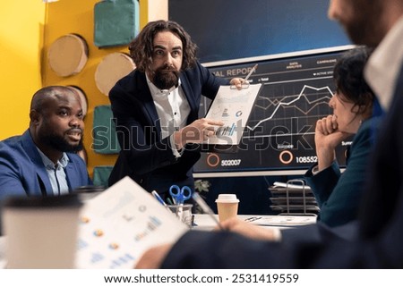 Angry stressed manager working under pressure with his staff, studying infographics and making changes for enterprise development. Tensed forecast associates meeting in boardroom space.