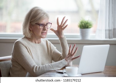 Angry stressed senior middle aged business woman annoyed with computer problem, old office worker hates stuck laptop, mad mature lady frustrated about bad online news, data loss, software failure