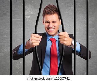 angry strong businessman bending the bars of his prison trying to get out