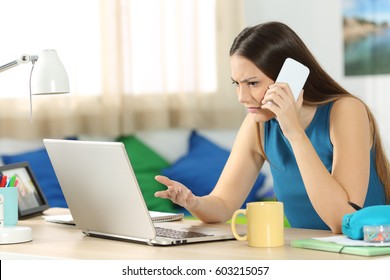 Angry Student Looking At A Laptop And Consulting On Phone With Customer Service In Her Bedroom In A House Interior