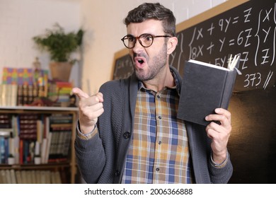 Angry Teacher Pointing With Finger In Classroom
