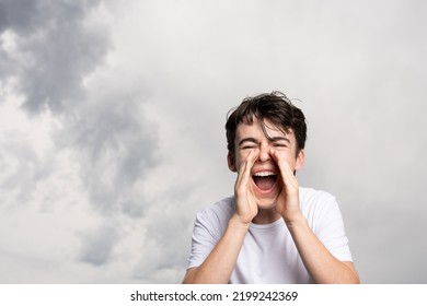 Angry Teenager Boy Shouting Under Dramatic Sky With Copy Space