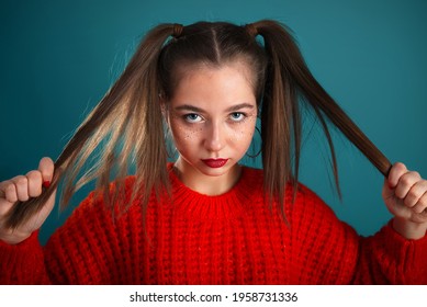 Angry Teenager Girl Face Portrait With Long Hair In Hands. Teenager Kid In Red Sweeter Looking Into The Camera.