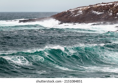 An Angry Turquoise Green Color Massive Rip Curl Of A Wave As It Barrels Rolls Along The Ocean. The White Mist And Foam From The Wave Are Foamy And Fluffy. The Ocean In The Background Is Deep Blue. 