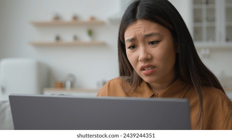 Angry upset Asian japanese woman girl homeowner using laptop in kitchen has problem stressed about mistake software error bug virus worried businesswoman work from home reading bad news fail business - Powered by Shutterstock