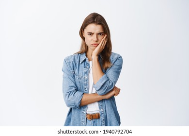 Angry and upset blond girl frowning, looking with dismay and hate, sulking and staring at camera something unfair and disappointing, standing against white background - Shutterstock ID 1940792704
