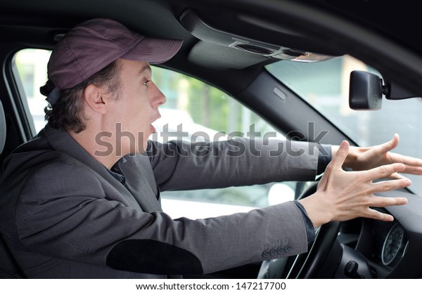 Angry upset man protesting against something or\
someone while driving his\
car