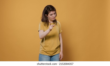 Angry upset woman arguing showing index finger pointing at guilty person punishing mischief in studio. Shouting girl looking unhappy and displeased asking for obedience and demanding respect.