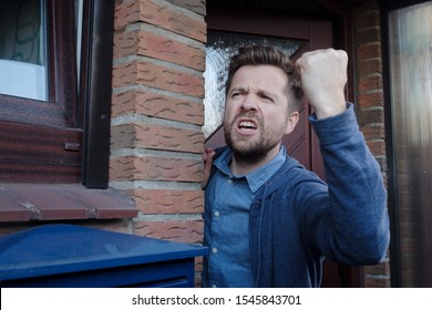 Angry Upset Young Male Neighbor With Fist In Air, Open Mouth Yelling Standing Near Door. Negative Emotions, Facial Expression Reaction