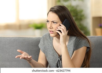 Angry Woman Arguing During A Phone Call Sitting On A Couch In The Living Room At Home