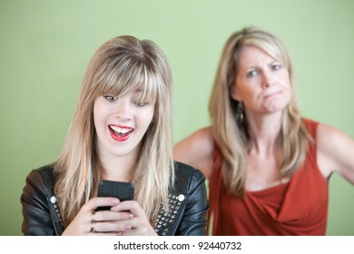 Angry Woman Behind Excited Teen On Mobile Phone