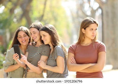 Angry woman being ignored by her happy friends who are checking smart phone content in the street - Shutterstock ID 1931206796