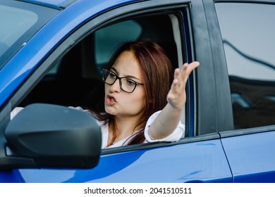 Angry Woman Driver Stuck In Traffic. An Aggressive Woman Driving A Car Shouting At Someone.