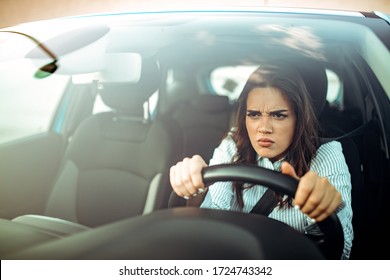 Angry woman driving a car. The girl with an expression of displeasure is actively gesticulating behind the wheel of the car. Angry business woman in a car. Stress girl in a car - Shutterstock ID 1724743342