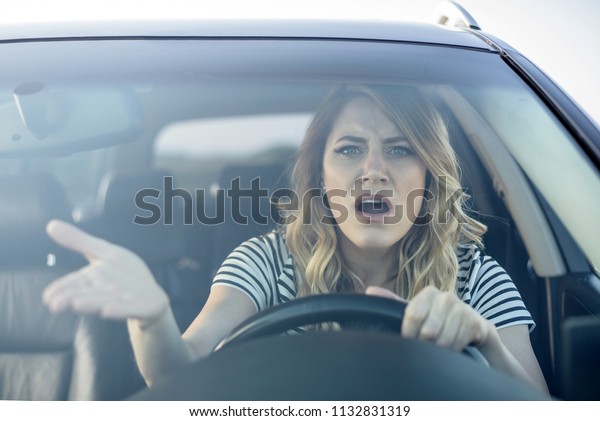 Angry\
woman driving a car. The girl with an expression of displeasure is\
actively gesticulating behind the wheel of the\
car.