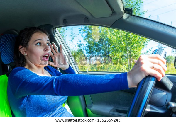 Angry woman driving a car. The girl with an
expression of displeasure is actively gesticulating behind the
wheel of the car. Car insurance
concept