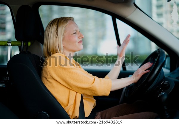 Angry woman driving a car. Upset young woman driving\
car in city