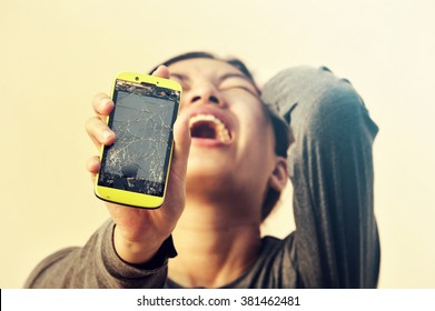 Angry woman holding broken smart phone 