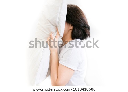 angry woman with insomnia yelling and holding pillows while sitting in bed