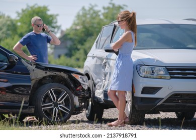 Angry woman and man drivers of heavily damaged vehicles calling insurance service for help in car crash accident on street side. Road safety concept - Shutterstock ID 2137918791
