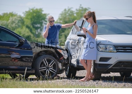 Angry woman and man drivers of heavily damaged vehicles calling insurance service for help in car crash accident on street side. Road safety concept