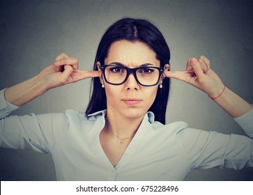 Angry woman plugging her ears with fingers 