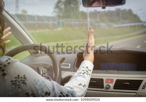 Angry woman screaming and gesturing\
while driving a car. Negative human emotions\
concept