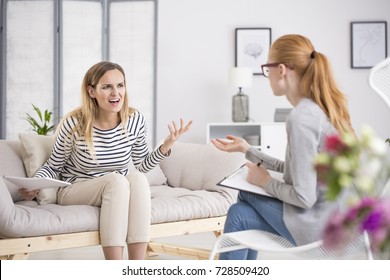 Angry Woman Screaming While Sitting On Beige Settee During Therapy With Psychiatrist. Psychotherapy Concept.