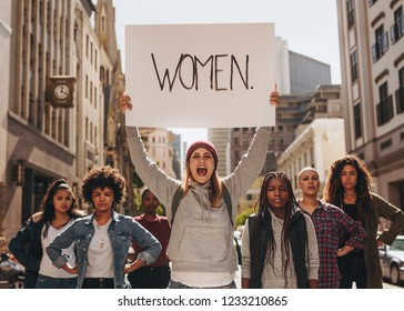 Angry Woman Shouting With A Hand Written Protest Sign At Women's March. Group Of Diverse Females Demonstrating Outdoors On City Street.