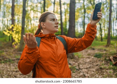 Angry woman tourist hiker hand holding smart phone searching signal in the forest. Communication, cellular problem, bad connection. No signal cellphone network. No communication coverage, lost contact
