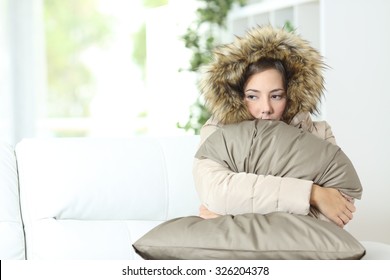 Angry woman warmly clothed in a cold home sitting on a couch