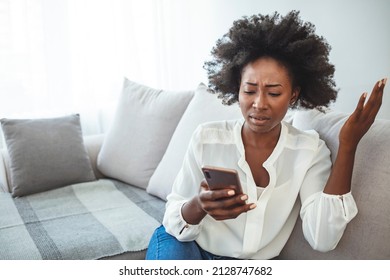 Angry Young African Woman Looking At Smartphone, Frustrated With No Signal Or Message Of Deception, Crazy Woman Disappointed Reading Bad News On Phone, Upset Girl Gets Negative Answer Or Rejected