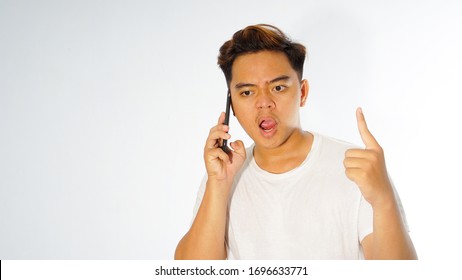 Angry Young Asian Man Calling On The Phone And Complaining Due To Customer Inconvenience Standing With White Shirt On White Background, Male Fells Upset And Mad While Having Conversation On His Phone