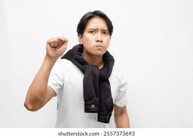 Angry young Asian man shouting with clenched fist, expressing intense frustration and rage. Ideal for themes of anger, conflict, or emotional outbursts - Powered by Shutterstock